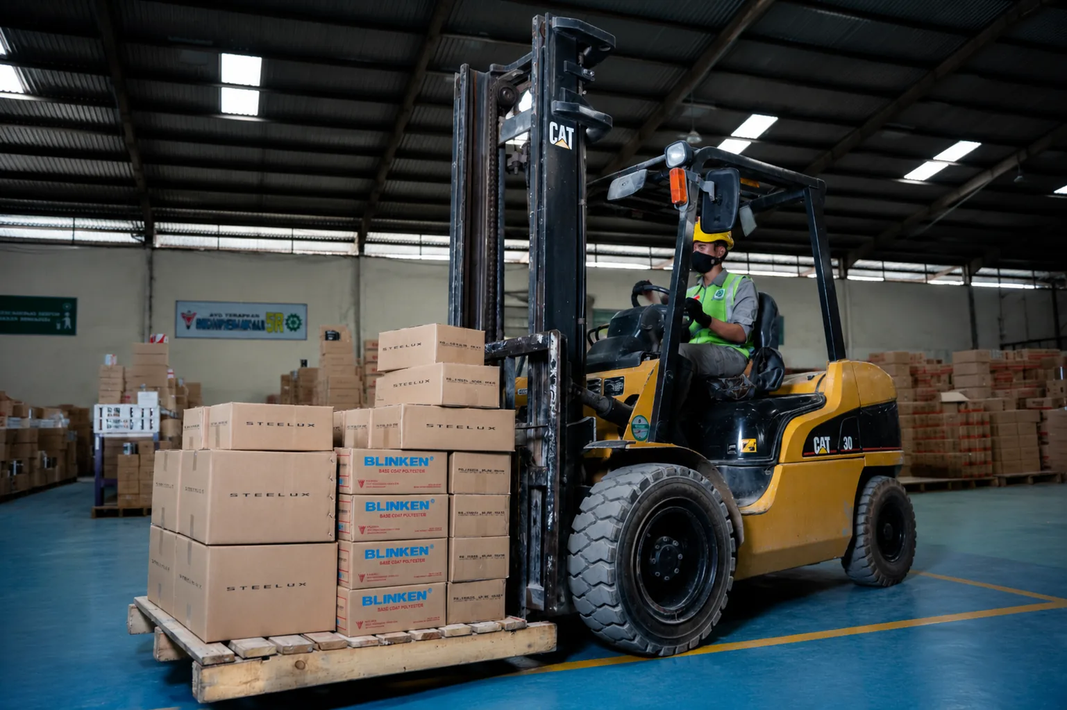 Forklift moving pallets of Steelux and Blinken cartons inside the VK warehouse